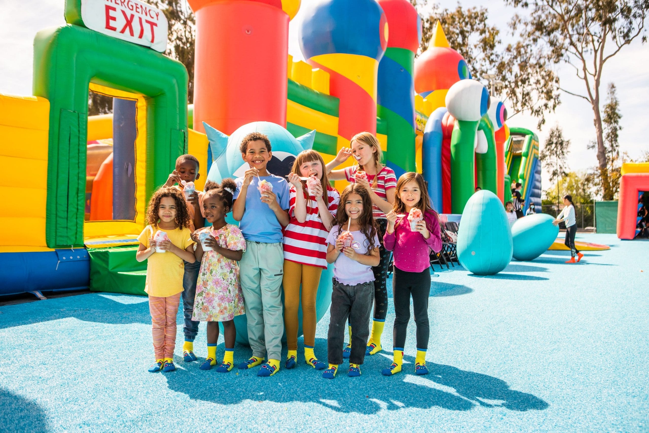 Kids smiling in the sun next to a giant inflatable area. An illustration for Funbox Virginia Beach